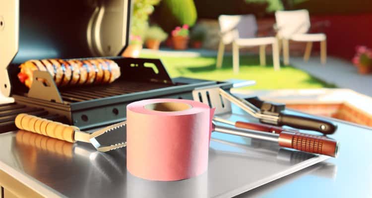 BBQ tools and pink butcher paper roll outdoors
