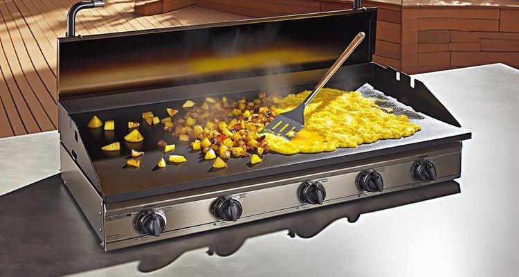 complete breakfast hash being combined on griddle with spatula, eggs coating potatoes and sausage