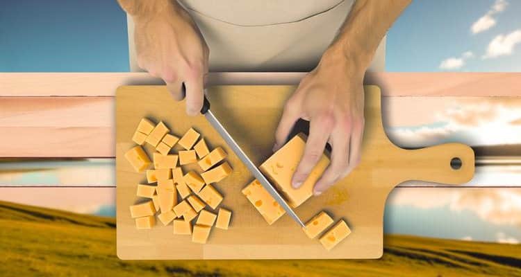 Overhead view of cutting cheddar cheese into blocks for cold smoking
