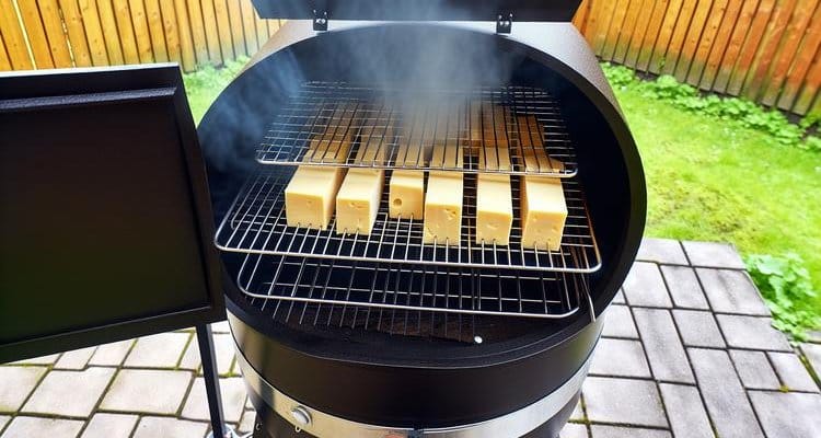 Cold smoking cheese setup showing open pellet smoker with cheese blocks on wire racks