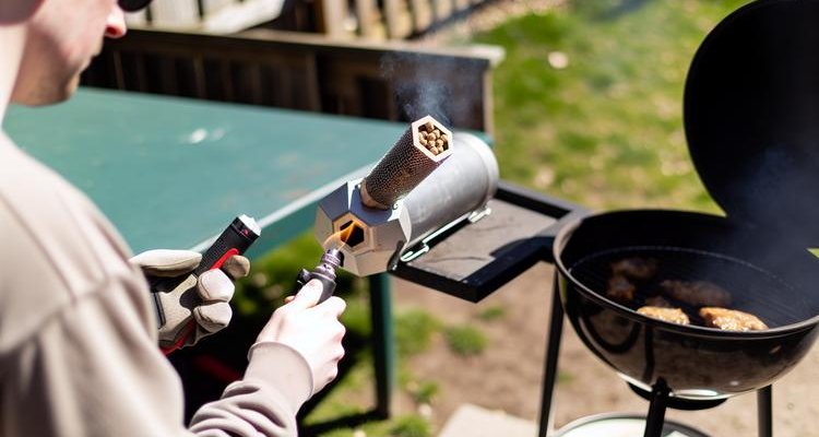 Person lighting smoke tube with propane torch demonstrating proper technique