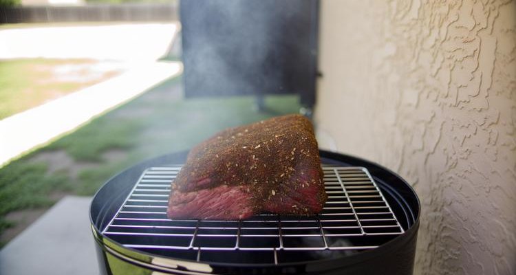Pastrami brisket with peppercorn rub smoking on grill grate