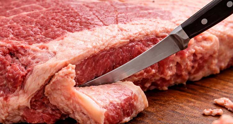 Close-up of boning knife removing hard fat deposit from underside of brisket