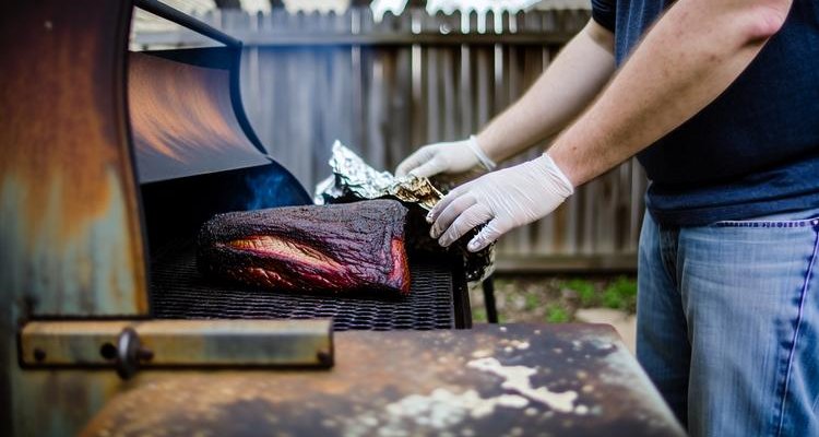 unwrapping finished smoked brisket revealing steaming juicy meat with perfect mahogany crust and smoke ring