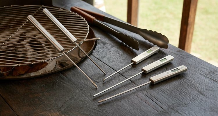 Big green egg thermometer probes and grill grate on dark wood surface