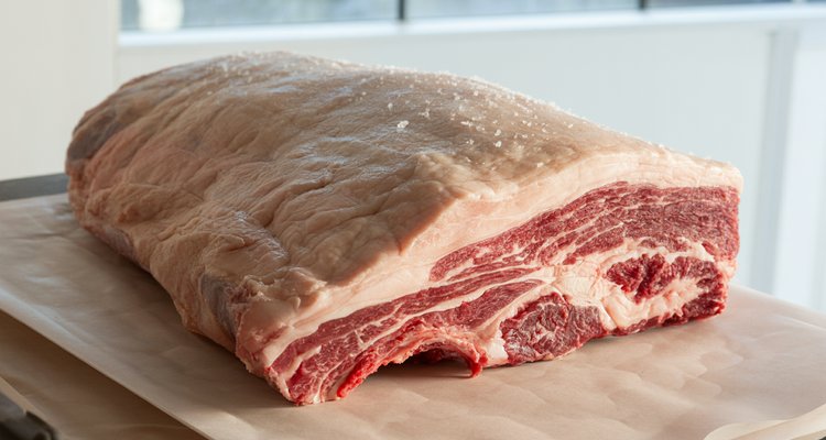 Whole raw packer brisket showing the flat and point sections on a butcher block
