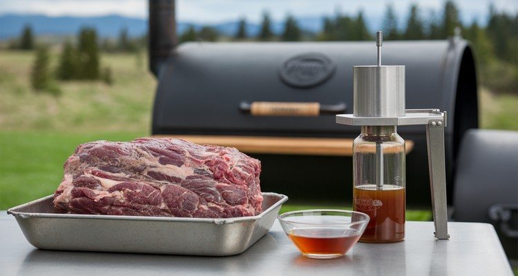 Trimmed brisket with meat injector and beef broth injection ready for smoking