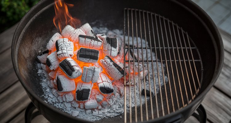 Overhead view inside a kettle grill showing two-zone charcoal arrangement with hot coals on the left and empty grate on the right for indirect cooking