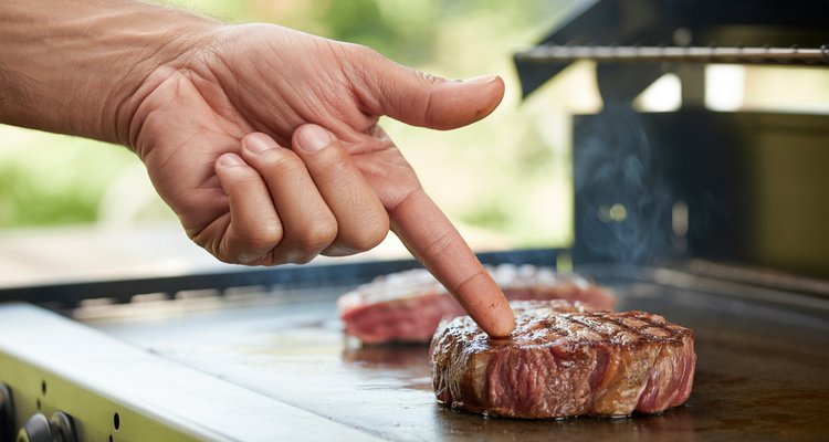 Hand demonstrating finger test technique for checking steak doneness