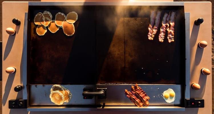 Flat top griddle cooking zones — pancakes, bacon, and eggs cooking simultaneously on an outdoor griddle barbecue