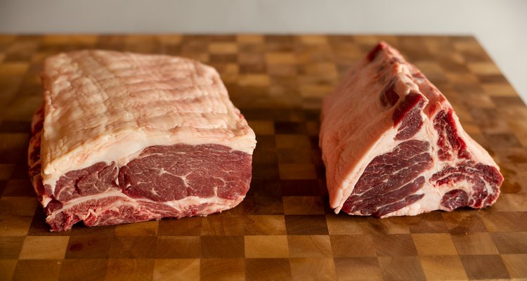 Brisket flat and point cuts separated side by side on a butcher block showing the rectangular flat and triangular point with heavy marbling