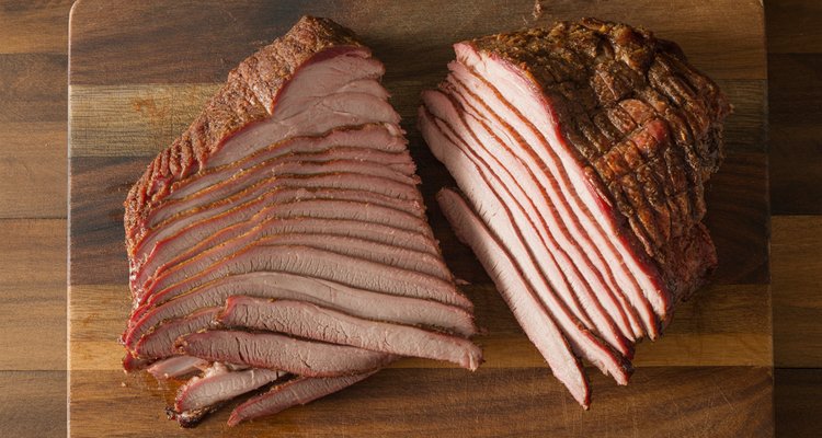 Close-up of brisket flat showing parallel muscle fibers with knife positioned perpendicular to demonstrate correct grain direction for slicing