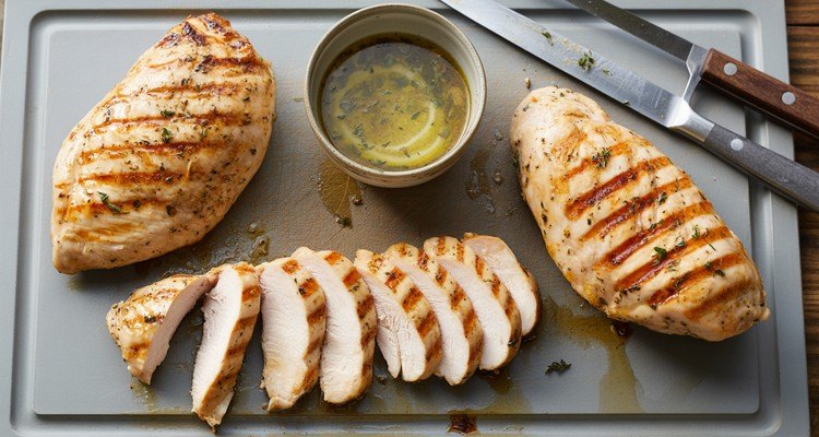 Rested grilled chicken breast sliced into juicy strips on a cutting board