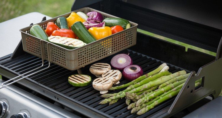 Colorful vegetables cooking in a grill basket on clean grill grates