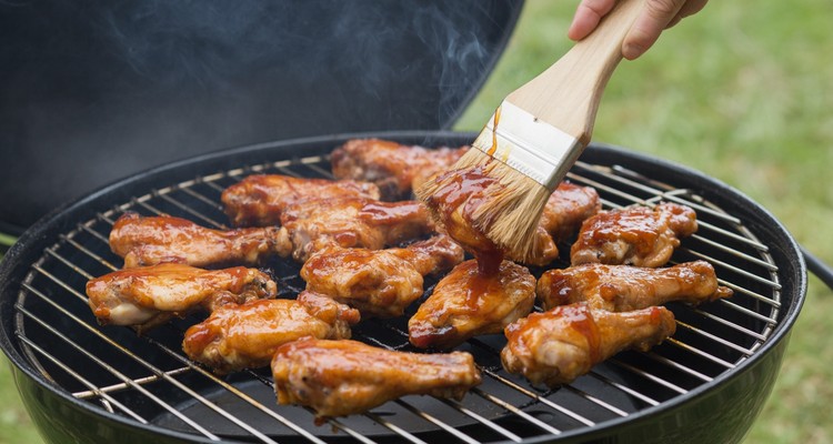 Honey BBQ wings being glazed on a grill grate