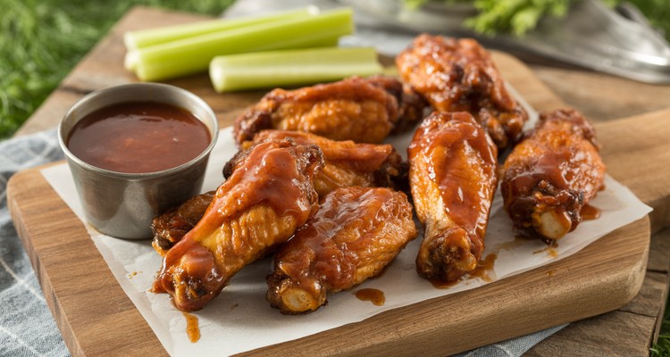 Crispy honey BBQ smoked wings coated in glossy sauce on a wooden board