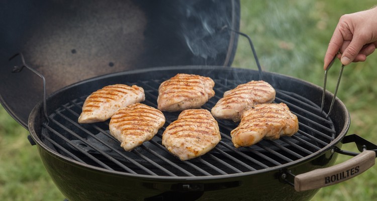 Chicken breasts with grill marks cooking on grill grates