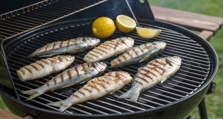 Fish fillets grilling on clean grill grates with lemon