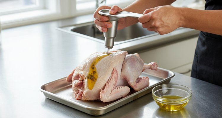 Hands injecting golden butter herb mixture into a raw turkey breast with a meat injector