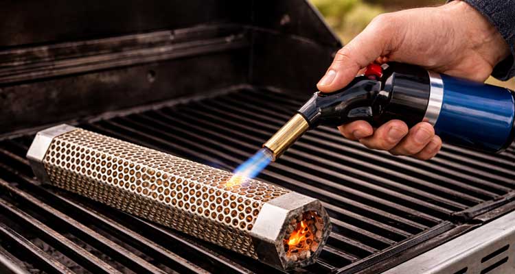 Person lighting smoke tube with propane torch demonstrating proper technique
