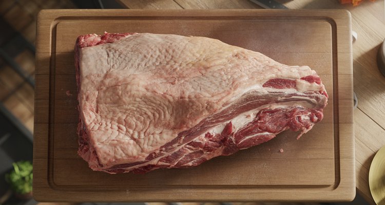 Whole packer brisket on a butcher block showing the flat and point sections with visible fat cap