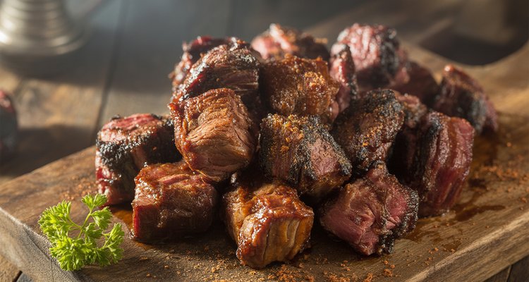 Poor man's burnt ends made from chuck roast on a wooden cutting board with glossy BBQ glaze