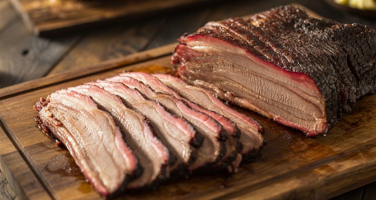 Sliced smoked brisket showing bark, smoke ring, and tender meat from both flat and point cuts
