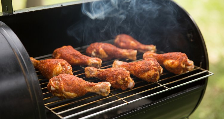 Chicken legs on smoker grates Seasoned chicken drumsticks on smoker grates with smoke wisps rising up