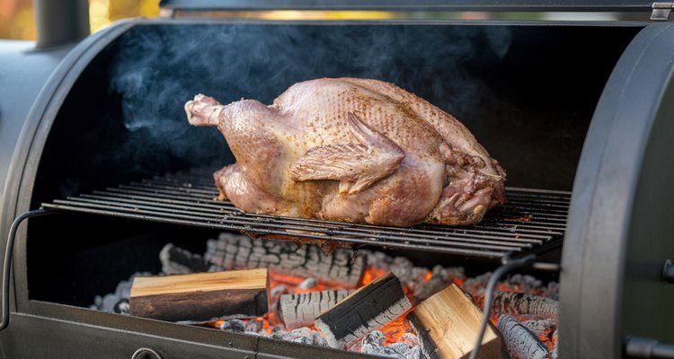 Whole goose smoking in an offset smoker with drip pan below