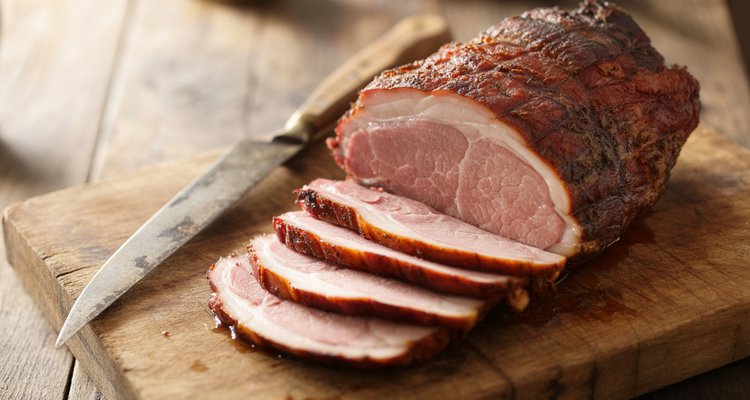 Sliced smoked pork loin on a cutting board showing a pink smoke ring