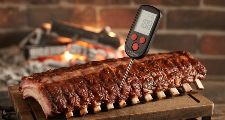 Checking internal temperature of smoked pork ribs Digital meat thermometer probe inserted in smoked pork ribs showing internal temperature on display