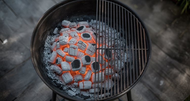 Overhead view of charcoal grill with coals banked to left half showing two-zone setup with empty cool side on right
