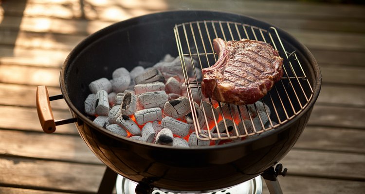 Charcoal grill showing two-zone setup with coals banked to one side for indirect cooking