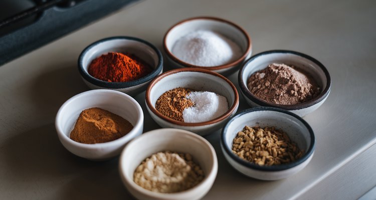 Small bowls of BBQ rub ingredients including paprika salt pepper sugar and spices