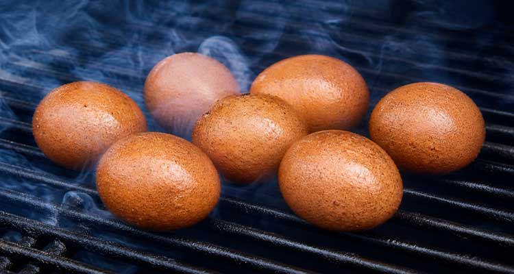 Smoked eggs on smoker grates with thin blue smoke