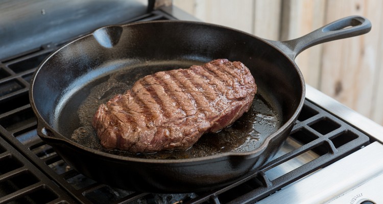 Smoked flank steak searing in a cast iron skillet
