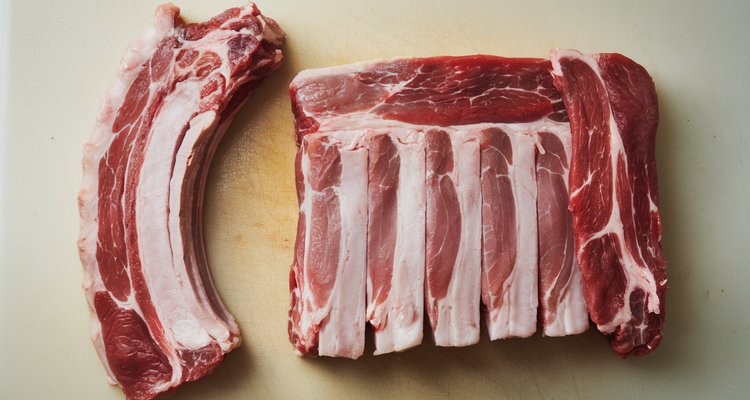 Raw St Louis style spare rib rack with breastbone cartilage and skirt meat trimmings placed beside it