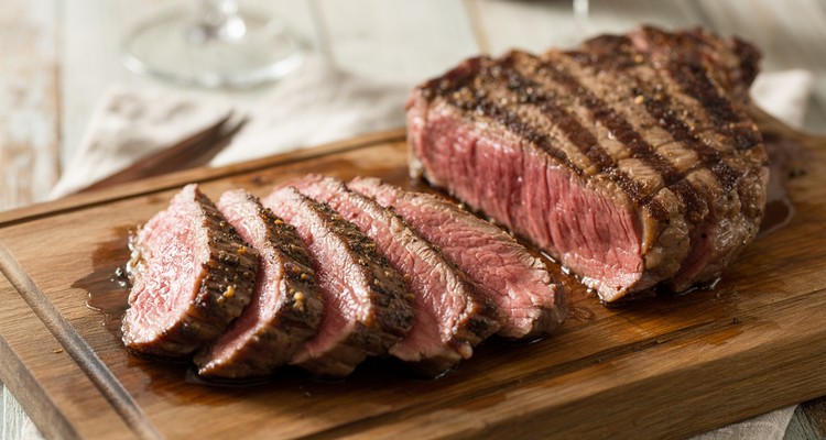 Sliced reverse-seared top sirloin steak on a rustic cutting board showing pink medium-rare interior