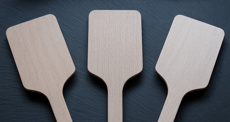 Three wooden grill cleaning scraper paddles fully visible on slate with smooth blank handles