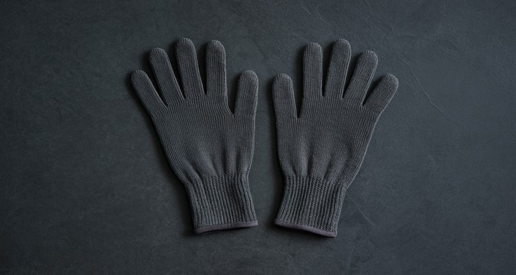 Pair of plain black heat resistant grill gloves on a dark slate surface