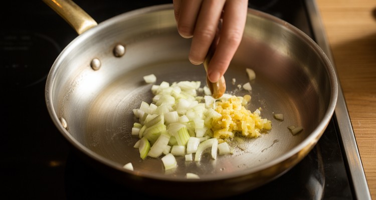 Building the Tikka Masala Sauce Base Diced onion and minced ginger garlic sauteing in ghee in a heavy pan for tikka masala sauce base