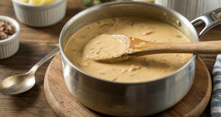 Creamy chicken cordon bleu sauce simmering in a saucepan, thick enough to coat the back of a wooden spoon