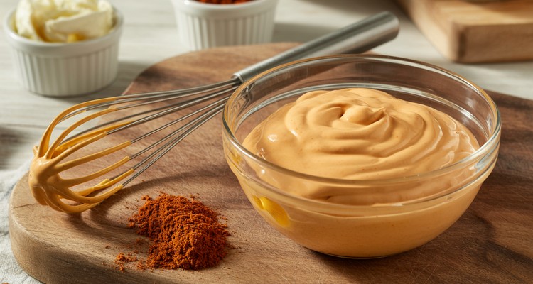 Creamy orange Popeyes-style sauce in a glass mixing bowl with a clean whisk resting beside it and smoked paprika blended smoothly into the mayonnaise Creamy orange Popeyes-style sauce in a glass mixing bowl with a clean whisk resting beside it and smoked paprika blended smoothly into the mayonnaise