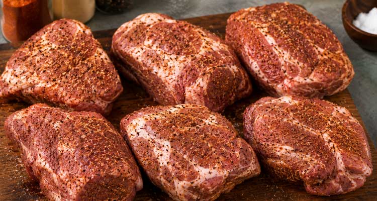 Seasoned pork pieces prepared on a cutting board before smoking