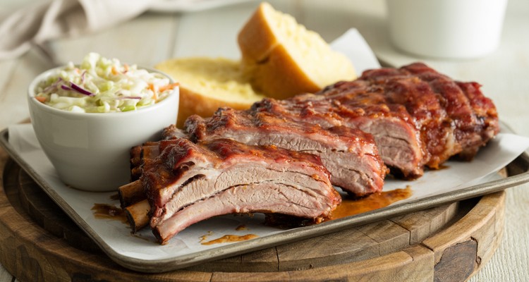 Finished Smoked Pork Ribs with Sides Sliced smoked pork ribs on a serving platter with coleslaw and cornbread sides