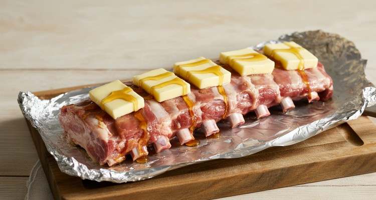 Wrapping Pork Ribs in Foil for the Texas Crutch Rack of pork ribs on aluminum foil with pats of butter and honey drizzle before wrapping
