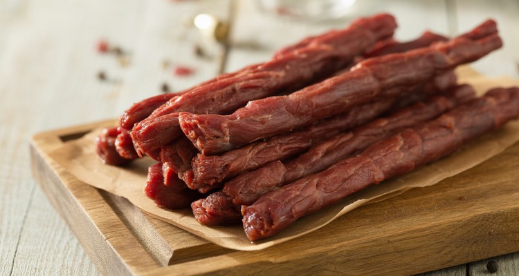 Homemade smoked beef sticks on a rustic wooden cutting board