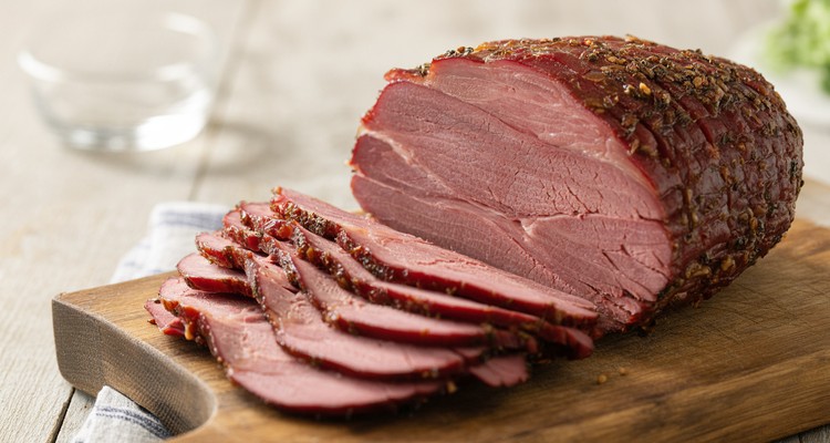 Sliced smoked corned beef on a cutting board showing dark peppery bark and pink smoke ring