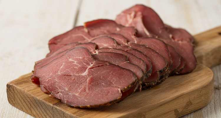 Thinly sliced smoked dried beef arranged on a rustic wooden board