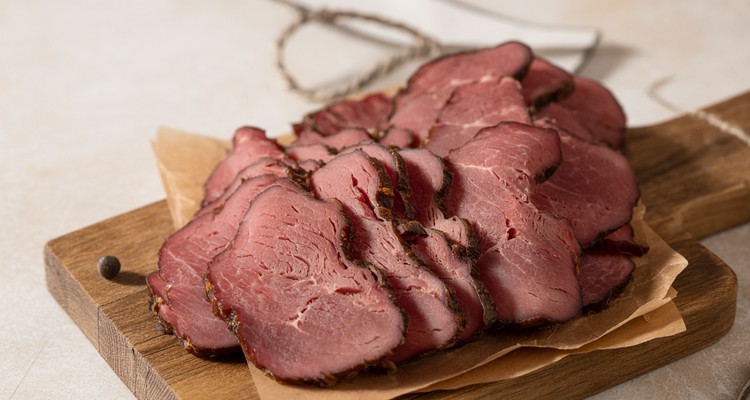 Thinly sliced smoked dried beef arranged on a rustic wooden board